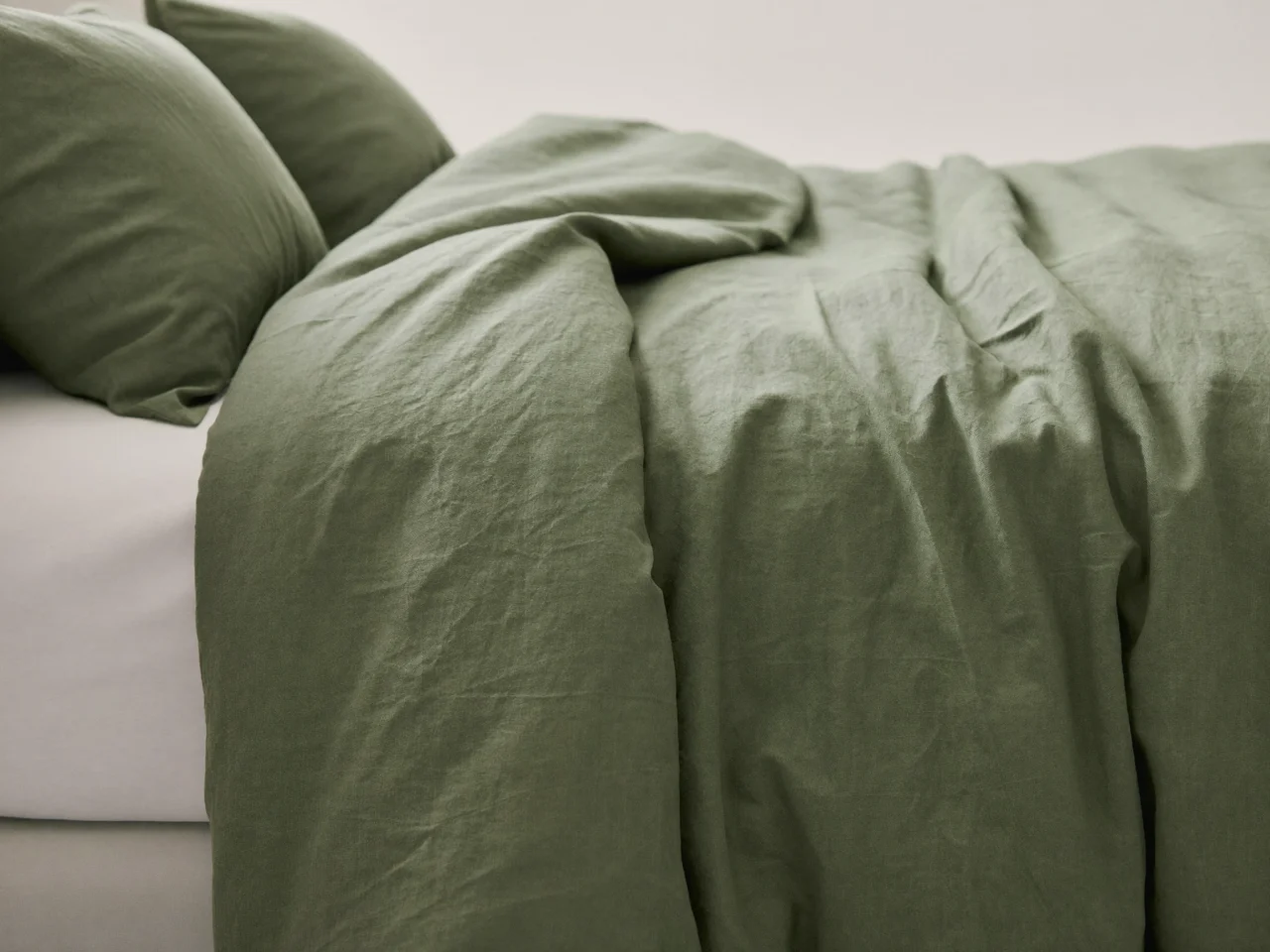 Housse de couette en lin lavé sauge sur un lit fait