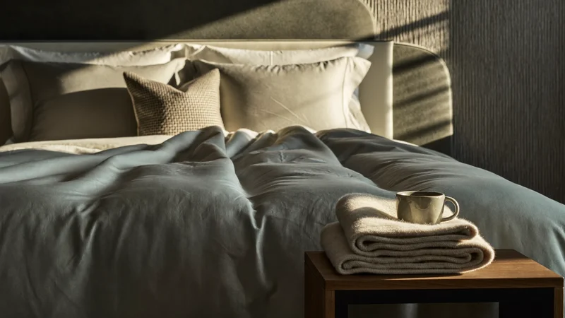 Ambiance de chevet avec literie froissée, tasse en céramique et plaid plié